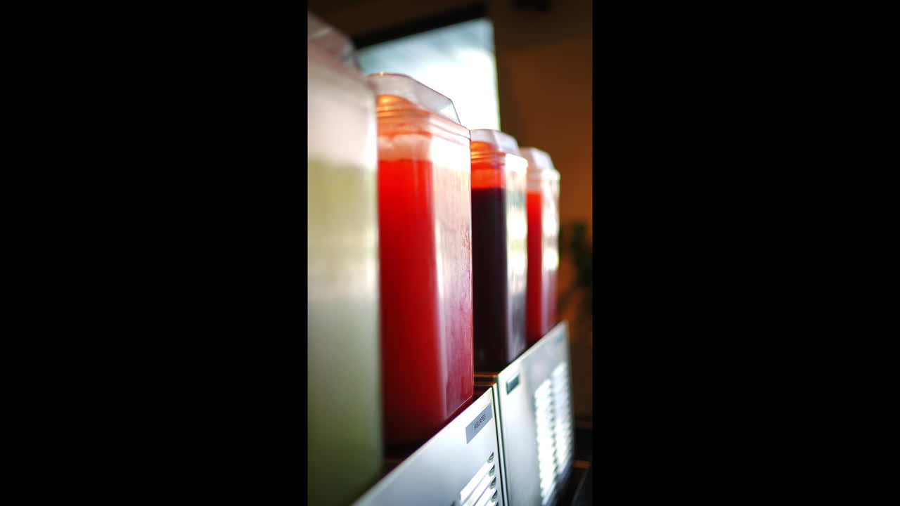 Metal rack displaying colorful juice dispensers with diverse beverages, presenting enticing beverage selection for restaurant or cafe customers