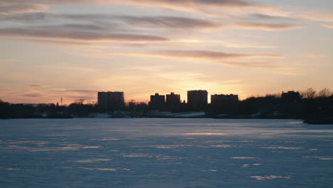 silhouetted city with frozen lake of nations in sherbrooke, quebec, canada during sunset