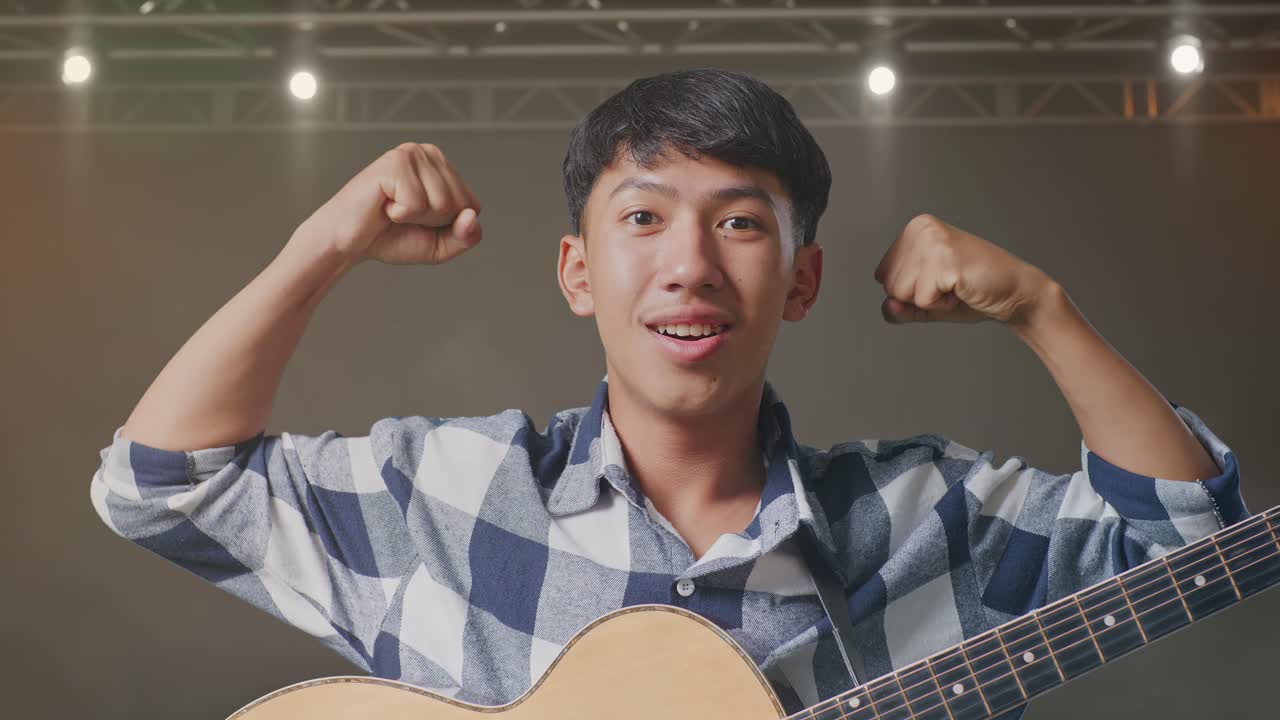 무대에서 기타 미소와 플렉스 근육을 가진 아시아 십대의 클로즈업
