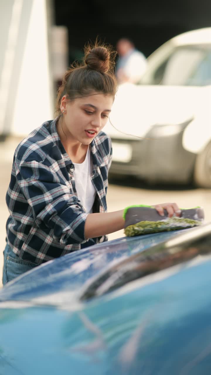 una mujer joven lavando un coche.