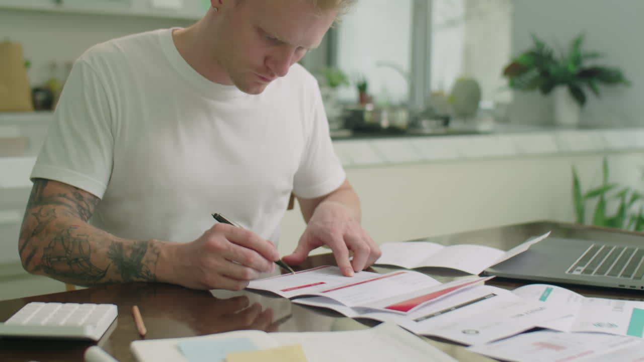Man Reading Bills and Counting Spendings with Calculator at Home