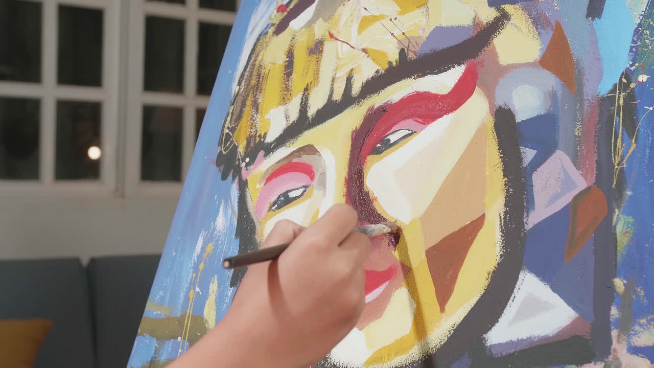 Close Up Of A Hand Holding Paintbrush Mixed Colour And Painting A Girl'S Face On The Canvas