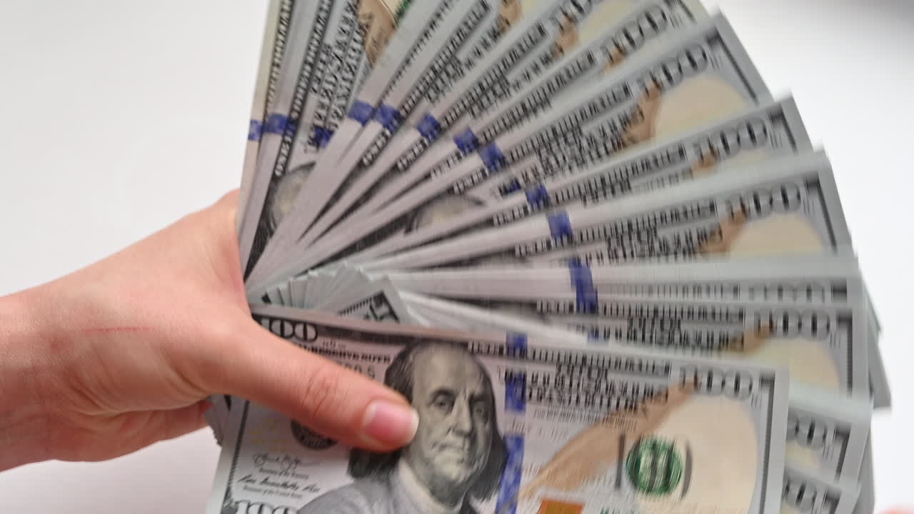 Close up of female hands holding a wide fan of one hundred dollar bills
