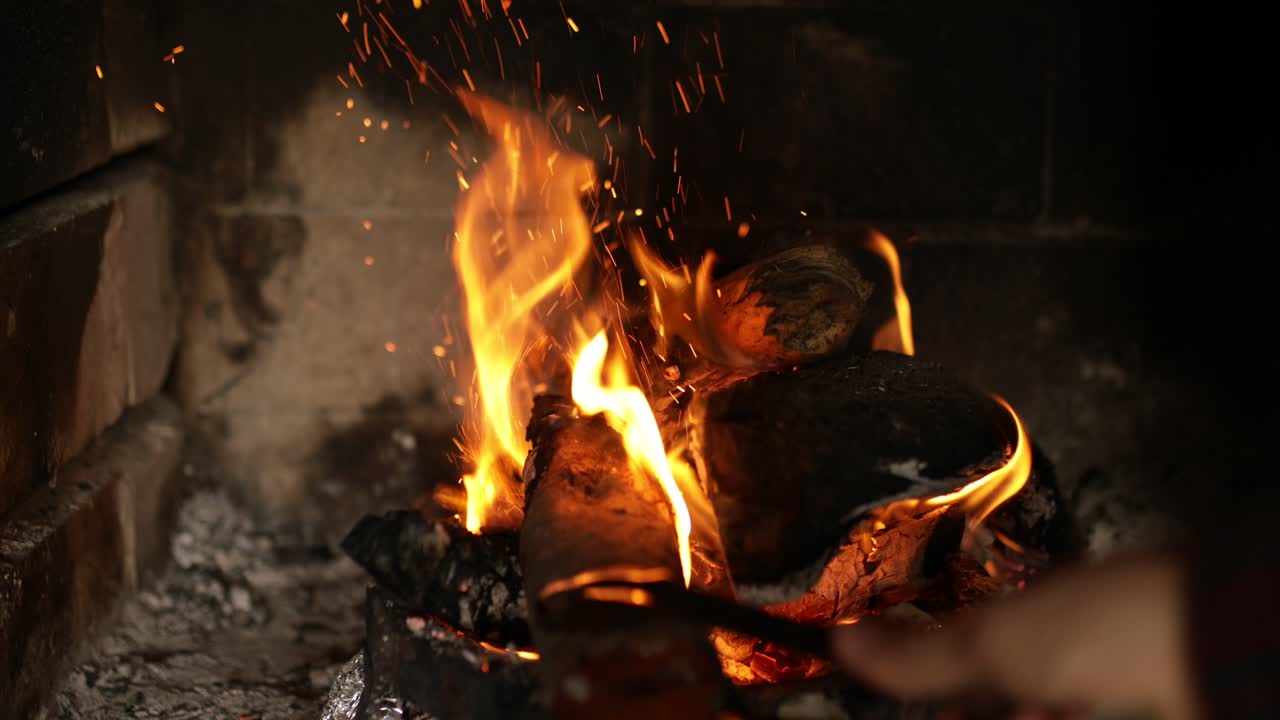 мужские руки подкладывают поленья в костер