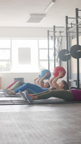 vertical video of diverse sportswomen exercising with medicine balls at gym in slow motion