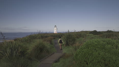 woman backpack traveler following coastal path towards waipapa lighthouse