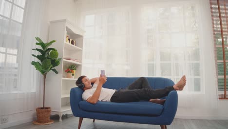 hombre escuchando música con teléfono inteligente en el sofá