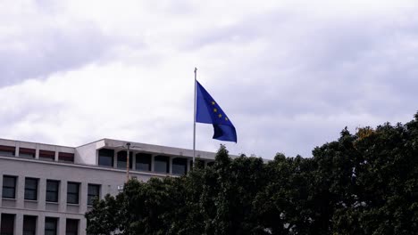 flag of europe with the circle of twelve stars flutters in the cloudy sky