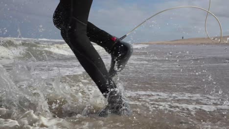 Action-shot-showing-surfer-wearing-wet-suit,-running-and-entering-the-sea-for-surfing