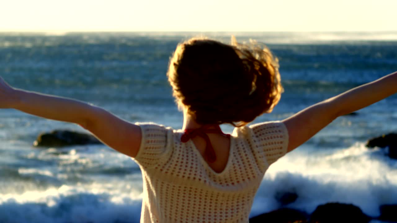 mujer de pie con los brazos extendidos en la playa 4k