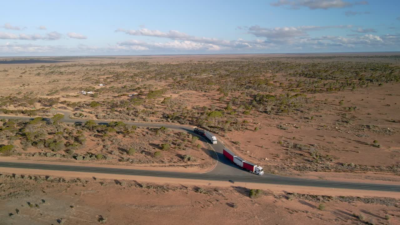 Aerial view of trucks on 90mile straight road, australia on a sunny, desert outback - pan drone shot
