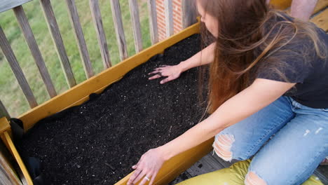 young woman preparing soil in garden bed