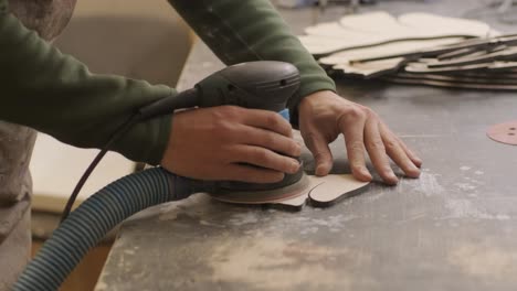 a carpenter grinds a piece of wood, plywood product made on a cnc laser machine with a grinder