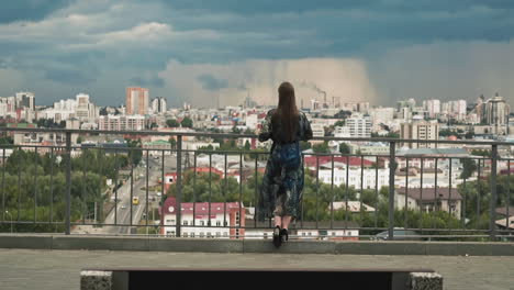 stylish woman looks at large modern city from viewing deck