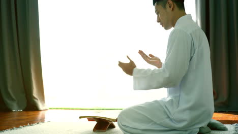 portrait of asian muslim man reciting surah al-fatiha passage of the qur'an, in a daily prayer at home in a single act of sujud called a sajdah or prostration