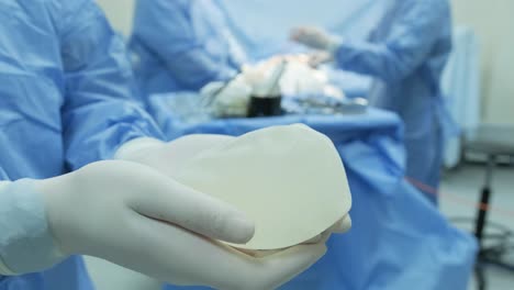 the surgeon prepares a sterile silicone breast implant for breast augmentation surgery