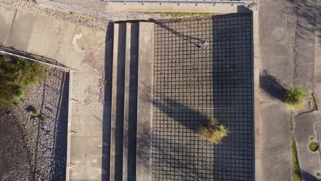toma aérea de arriba hacia abajo de un hombre saltando sobre formas geométricas en el piso frente al mar en buenos aires