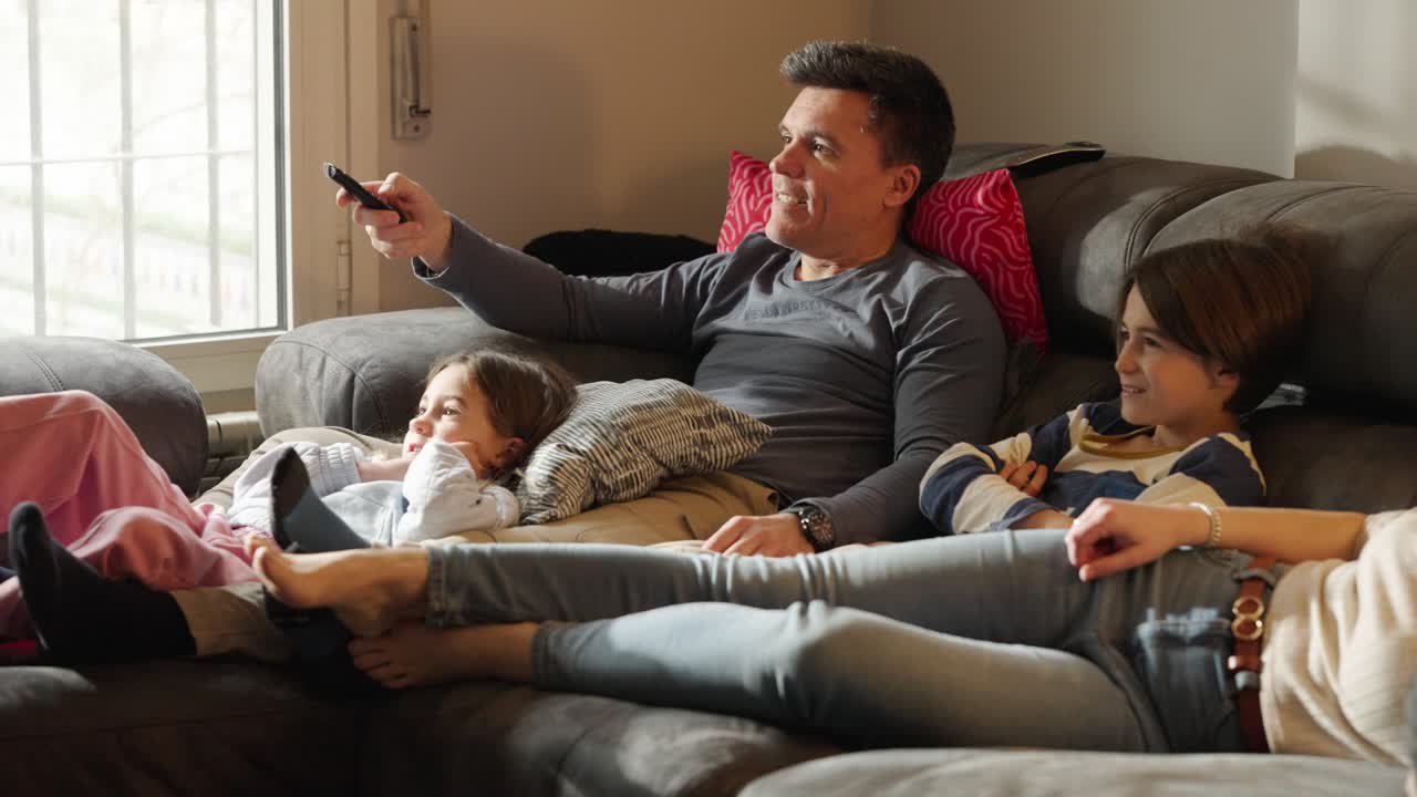 En familie slapper af på sofaen og ser tv.