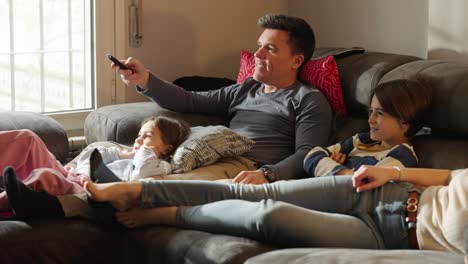 A family relaxing on the couch and watching TV