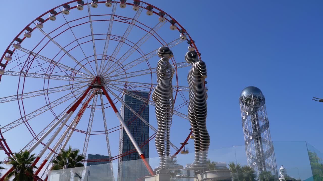 Ferris Wheel against the Blue Sky with Statue of Ali and Nino on embankment of Batumi