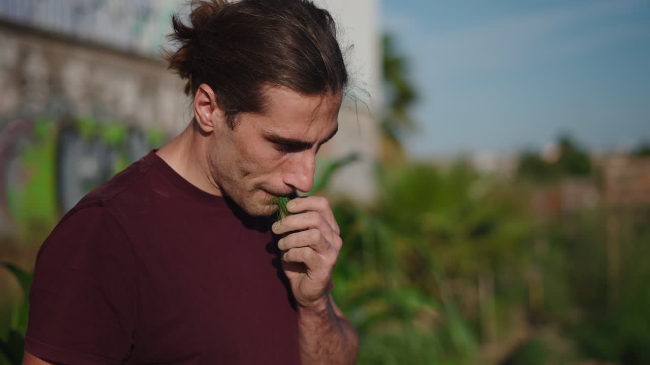Homem contemplativo cheirando grama verde fresca ao ar livre