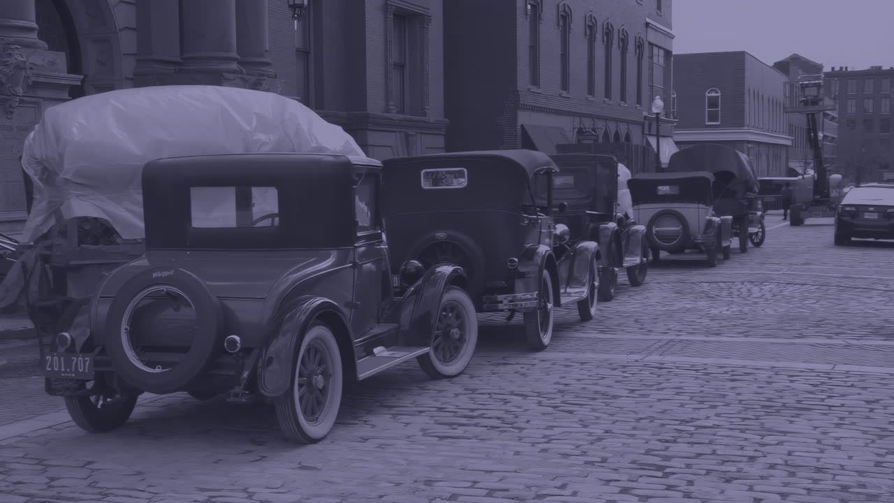 Scena film noir suggestiva di auto d'epoca degli anni '20 preparate per la produzione. Dotata di targhe finte storicamente accurate e stile fedele all'epoca. Grado cinematografico creativo applicato per un tocco di mistero
