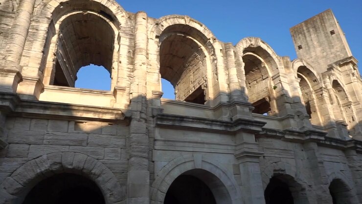 Vista ravvicinata dell'antico Teatro Romano di Arles, con archi e colonne monumentali in pietra sotto un cielo azzurro e limpido in Provenza, Francia.
