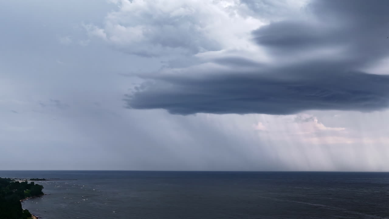 Dark storm clouds with lightning strikes forming over rural landscape with strong wind and dramatic light rain showers