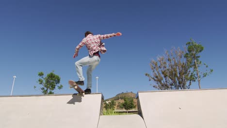 caucasian man riding and jumping on skateboard on sunny day