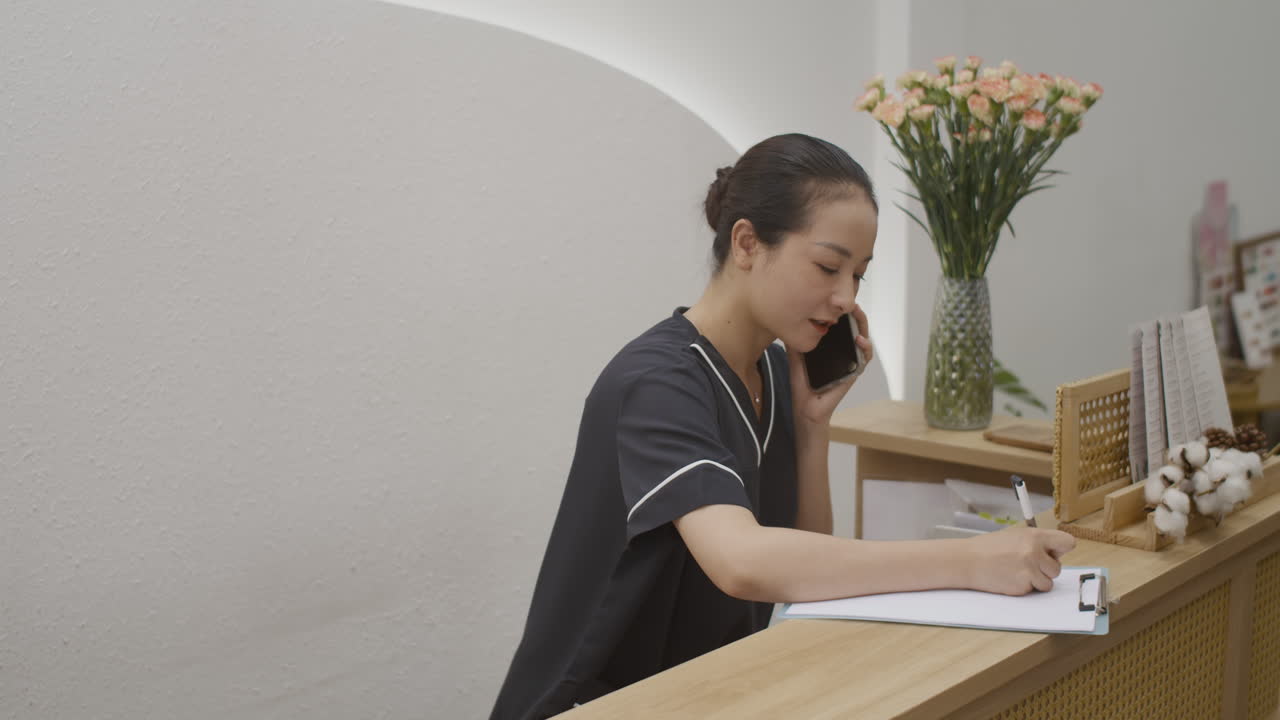 Spa Salon Receptionist Consulting Client on Smartphone