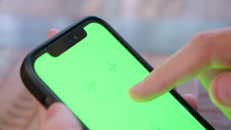 Close-up-of-top-of-iPhone-screen-being-tapped-and-swiped,-with-green-screen-for-replacement