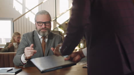 senior businessman discussing contract with partner in restaurant