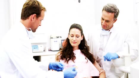 Dentist-showing-model-teeth-to-patient