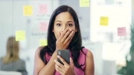 mujer mirando emocionada su teléfono en la oficina