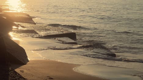 Concrete-blocks-and-cubes-dotting-the-shoreline,-caressed-by-waves,-partly-submerged-in-the-sand,-embracing-the-coastal-defense-aesthetic-with-an-artistic,-conceptual-flair