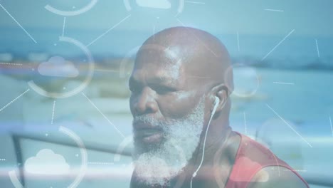 animation of media icons over senior african american man with earphones at beach