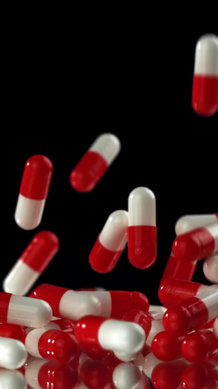 Red and White Capsules Falling on a Black Background