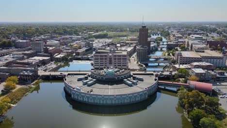 drone footage capturing downtown aurora, il, a chicago suburb in the chicagoland area, near the river, buildings, and the metra train line. crane up right day s