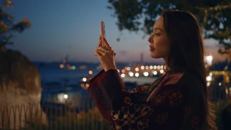 woman making panoramic photo twilight city from park observation deck close up.