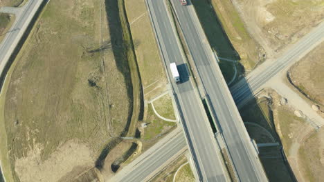 Vogelperspektive-Einer-Autobahnkreuzung-Mit-Über--Und-Unterführung,-Mit-Spärlichem-Verkehr-Und-Umliegendem-Unbebauten-Land