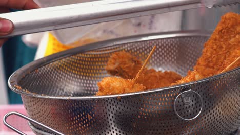 street food in asia - breaded chicken sticks left to drain in a metal bowl