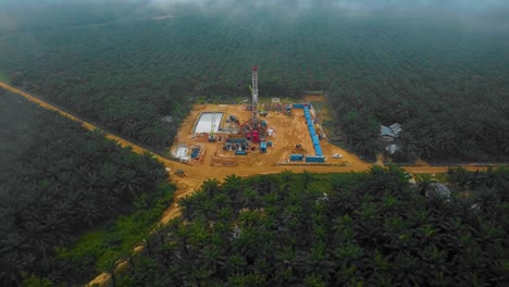 cinematic drone shot of onshore drilling and workover rig structure and rig equipment for oil exploration and exploitation in the middle of jungle surrounded by palm oil trees during sunset time