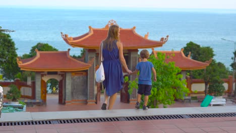 steadycam shot of a young woman and her son visiting a budhist temple ho quoc pagoda on phu quoc island, vietnam