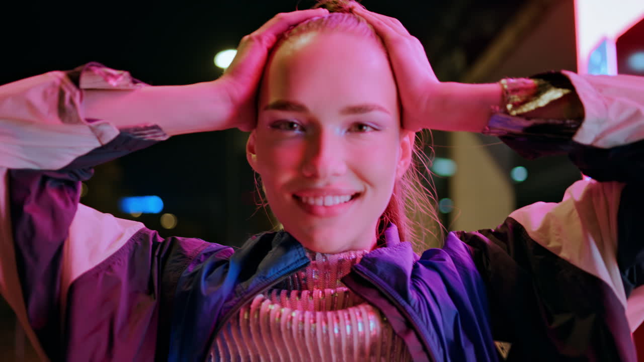 счастливая женщина наслаждается ночной жизнью, стоя рядом с неоновыми огнями.