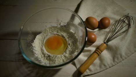 pouring egg yolk into glass bowl. raw egg falls into baking flour