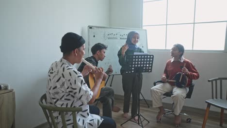 young asian students practicing sing and playing musical instruments together