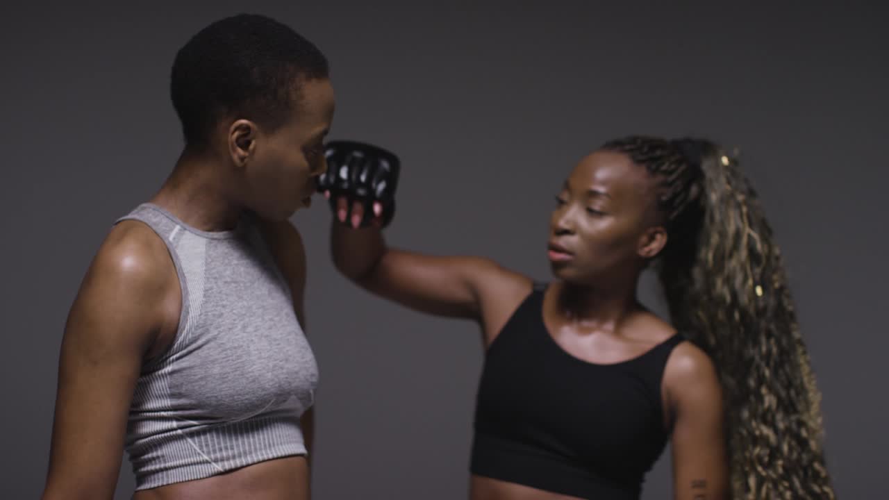 Studio Portrait Shot Of Woman Wearing Boxing Gloves Sparring With Trainer 3