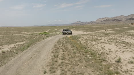 jeep driving slowly on sandy dirt road in arid steppe in georgia