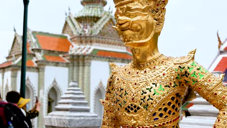 golden statue amidst temple visitors in bangkok