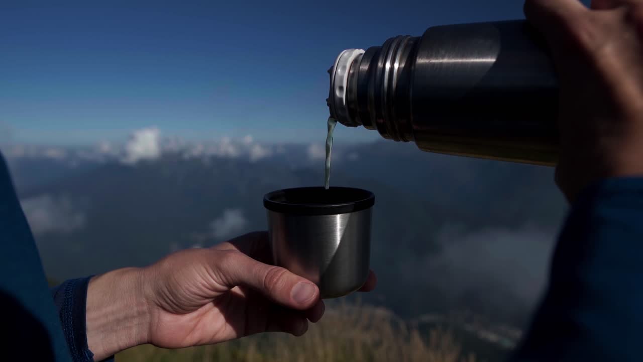 Close-up of Hands Pouring Hot Drink from Thermos in Mountains